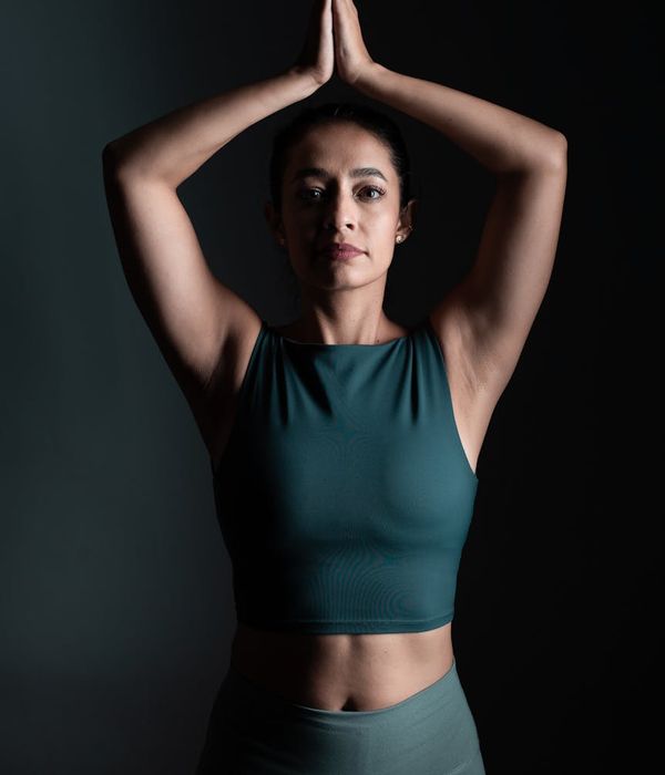 A woman in a calm, focused yoga pose against a light blue background.